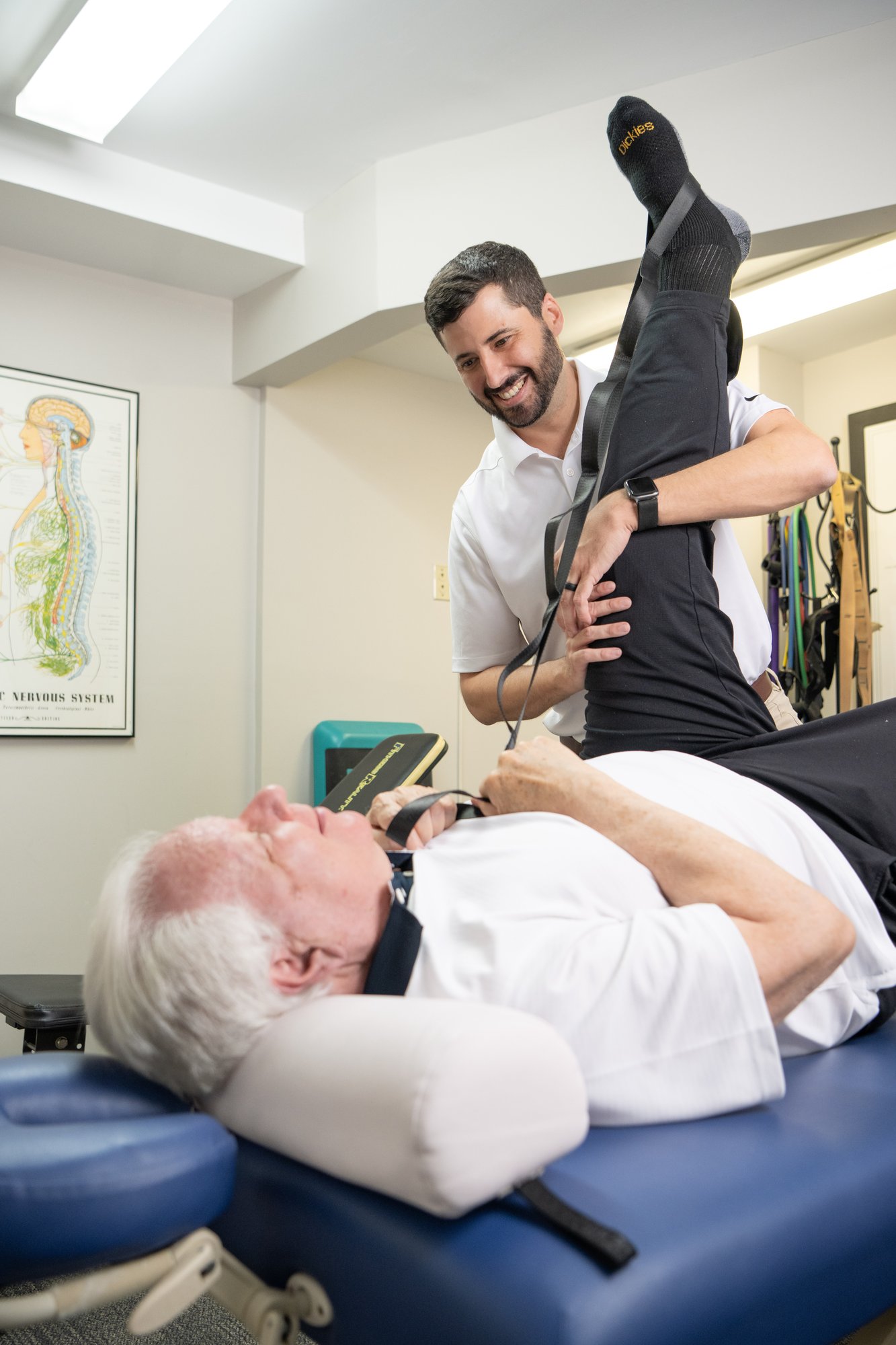 Russell Zeiss, DPT, assisting an older patient with a strap-assisted hamstring stretch